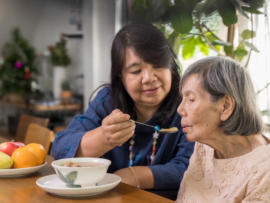 A caregiver feeds a client representing companion care and meal preparation in Boca Raton.