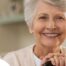 An older woman with healthy teeth smiles, representing good dental hygiene.