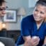 A nurse smiles as she helps an older couple with their medication in the comfort of their own home, showing the benefits of in-home nursing services.